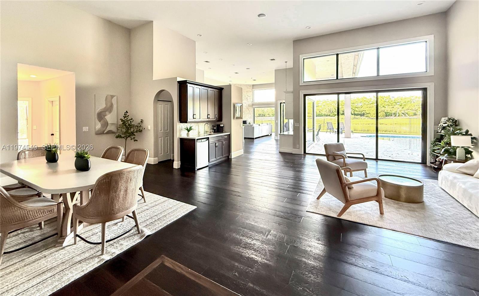 An open-concept living and dining area features dark wood floors, a wet bar, and large windows — 400 Alexandra Cir # 0, Weston FL 33326, WESTON, FL