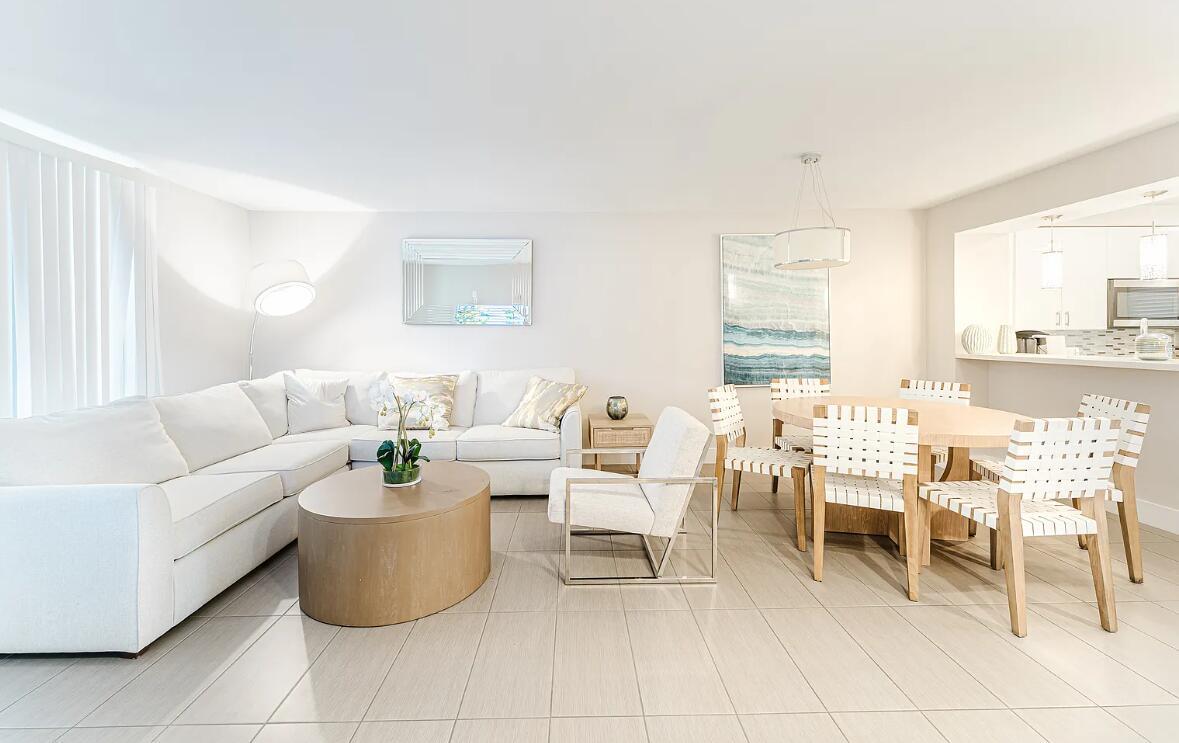 A bright open-concept living and dining area features white furniture, a wooden coffee table, and tile flooring — 601 N Ocean Boulevard, Boca Raton FL 33432, BOCA RATON, FL
