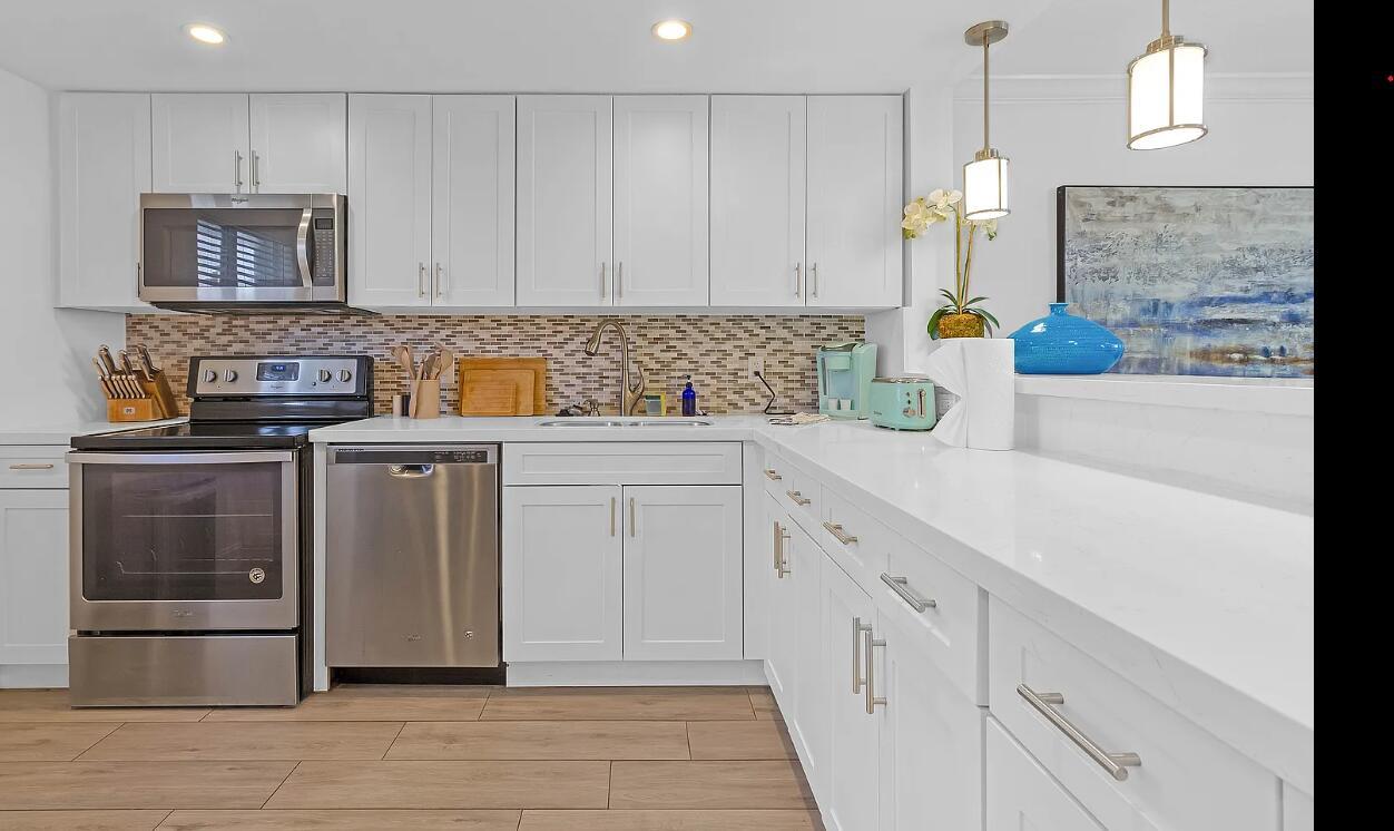 A modern kitchen features white cabinetry, stainless steel appliances, and a white quartz countertop — 601 N Ocean Boulevard, Boca Raton FL 33432, BOCA RATON, FL
