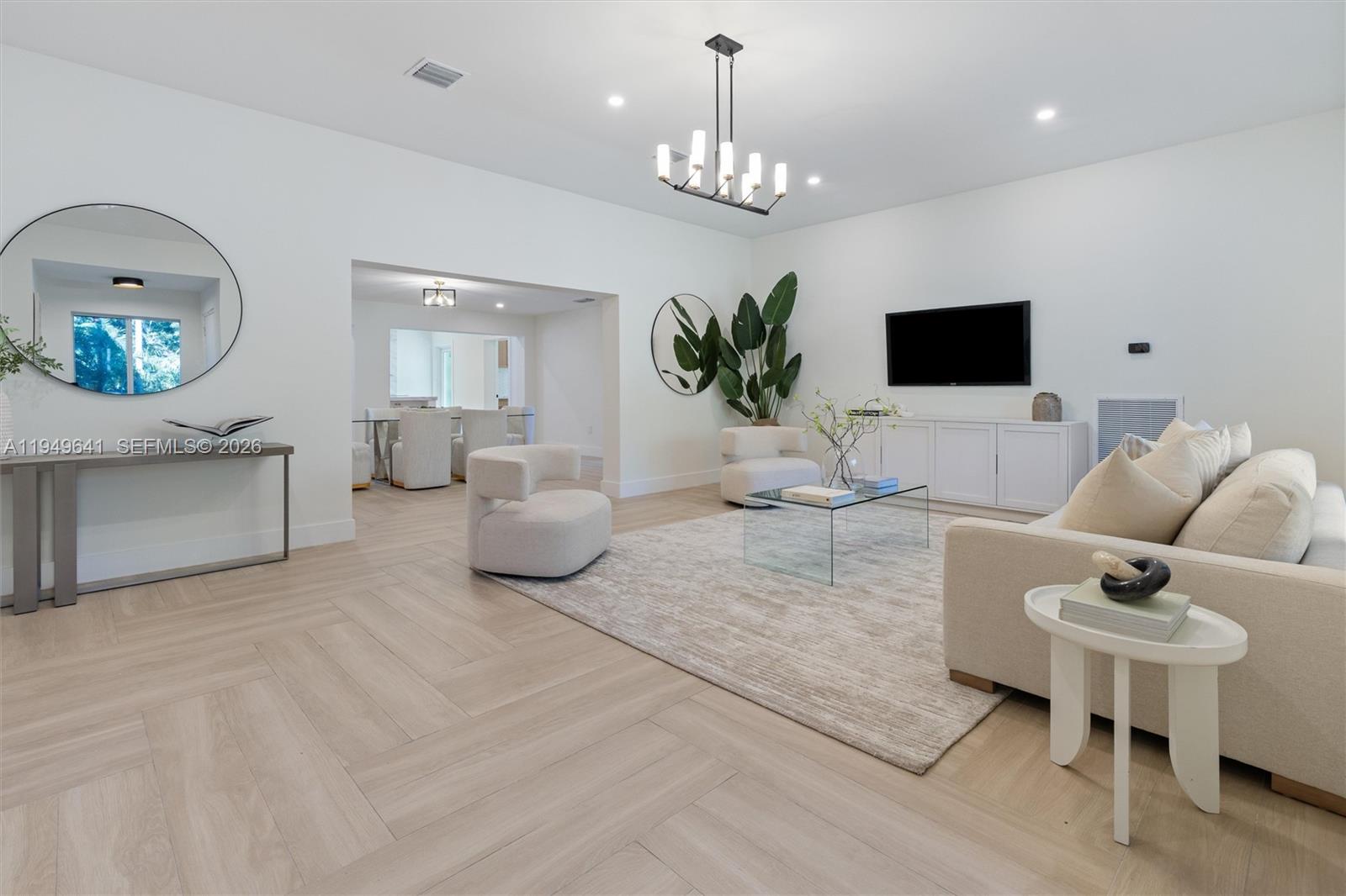 A bright living room features light wood herringbone floors, a white sofa, and modern decor — 420 NE 55th Ter, Miami FL 33137, MIAMI, FL