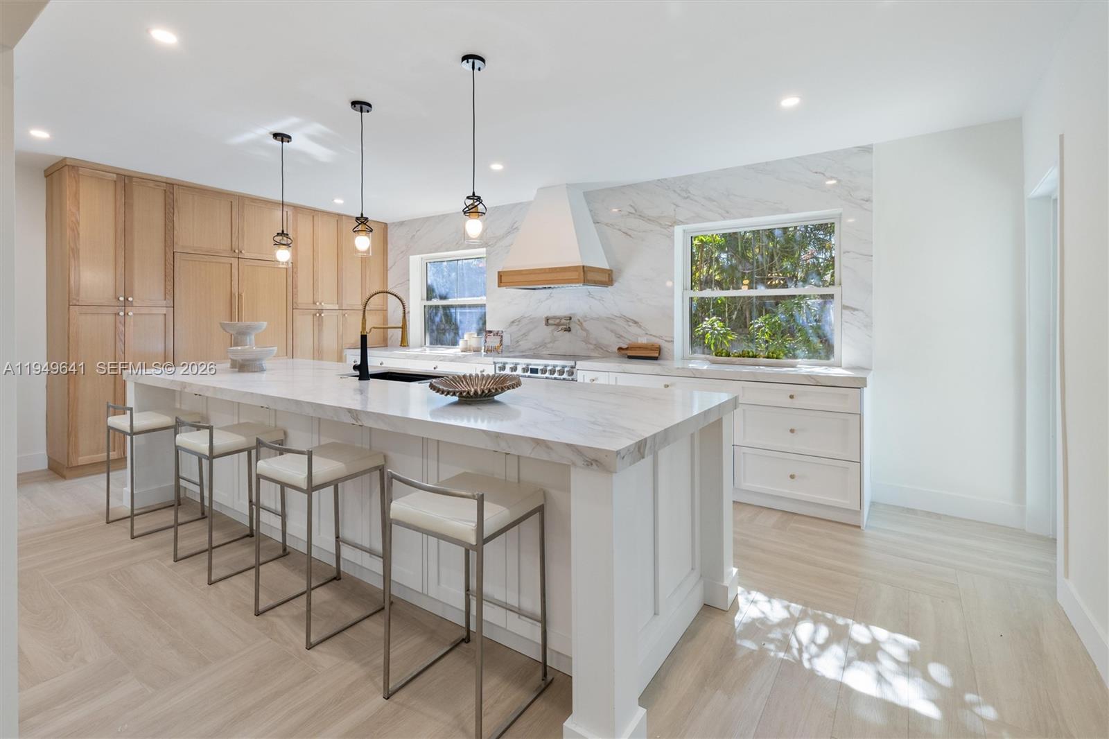 A modern kitchen features a large marble-topped island, light wood cabinetry, and white marble backsplash — 420 NE 55th Ter, Miami FL 33137, MIAMI, FL
