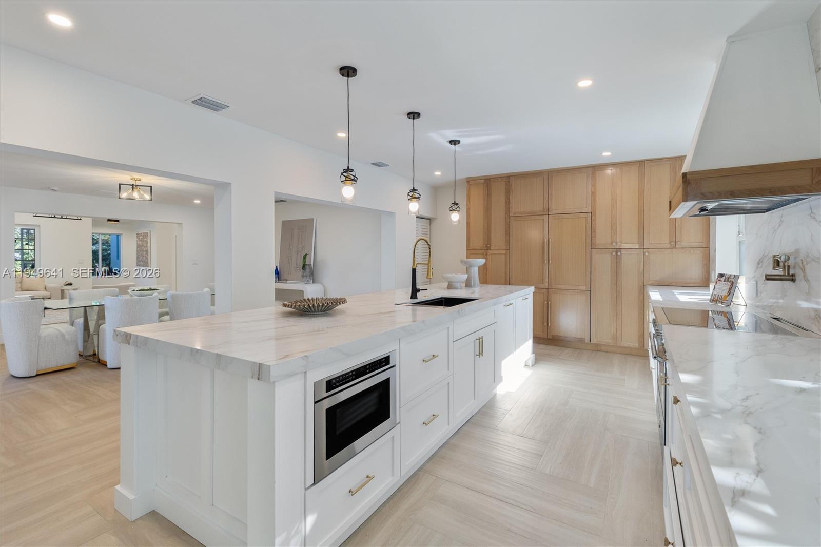 A modern kitchen features a white marble island, light wood cabinetry, and pendant lighting — 420 NE 55th Ter, Miami FL 33137, MIAMI, FL