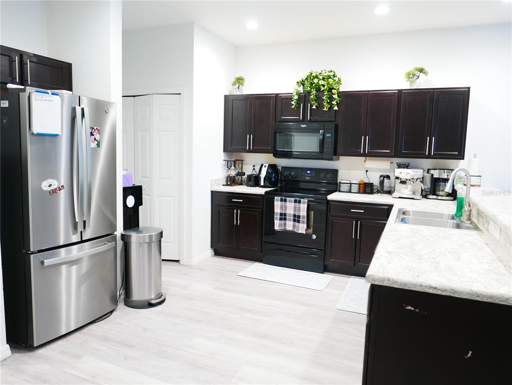 A kitchen features dark wood cabinets, stainless steel appliances, and light-colored countertops — 4769 VIGNETTE WAY, SARASOTA, FL