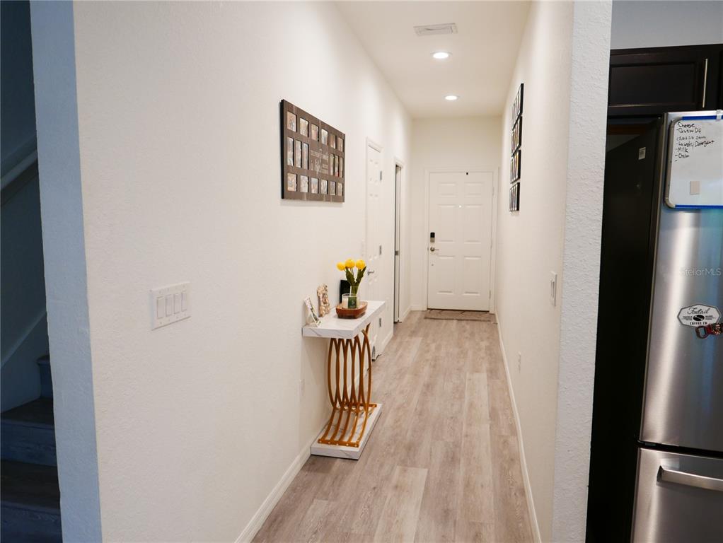 A hallway features light wood-look flooring, a white console table, and a white front door — 4769 VIGNETTE WAY, SARASOTA, FL