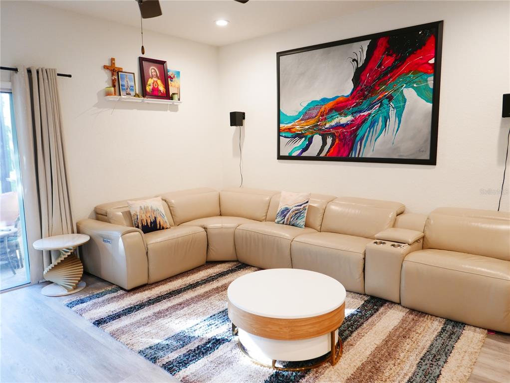 A living room features a beige sectional sofa, a round coffee table, and abstract wall art — 4769 VIGNETTE WAY, SARASOTA, FL