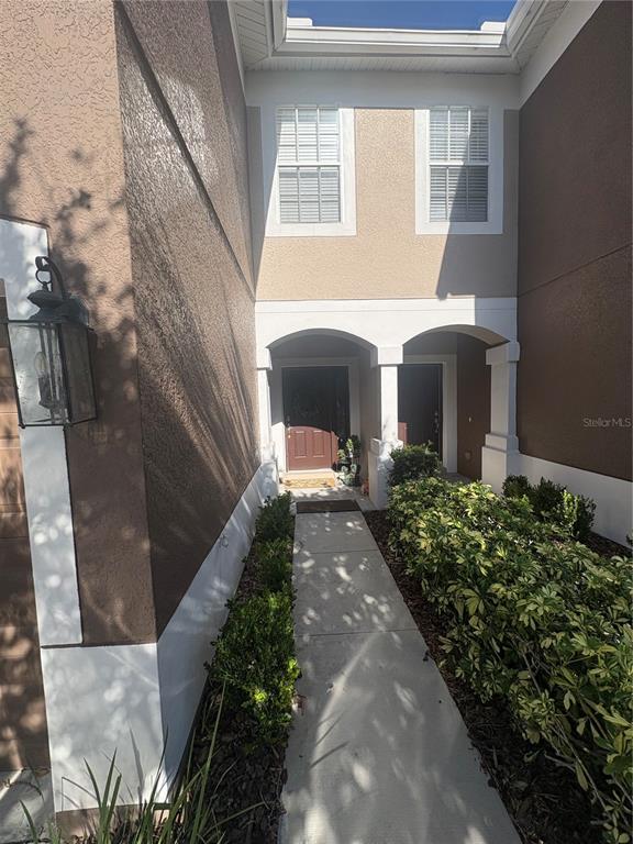 A concrete walkway leads to the covered entryway of a two-story stucco home — 4605 BARNSTEAD DRIVE, RIVERVIEW, FL