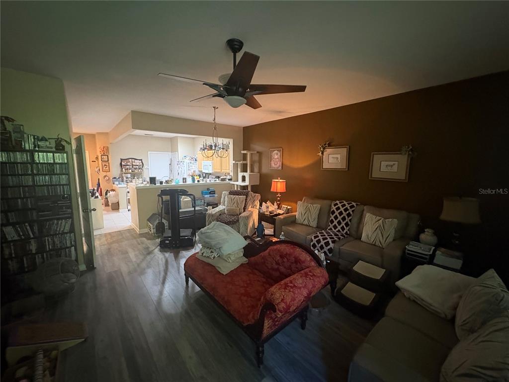 A living room with wood-look flooring, a ceiling fan, and a red chaise lounge — 4605 BARNSTEAD DRIVE, RIVERVIEW, FL