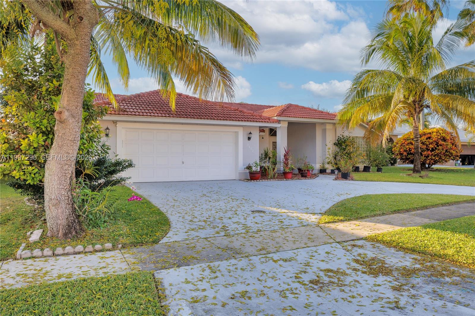 A single-story house with a white garage, red tile roof, and palm trees in front — 3462 Harness Cir # 0, Wellington FL 33449, WELLINGTON, FL
