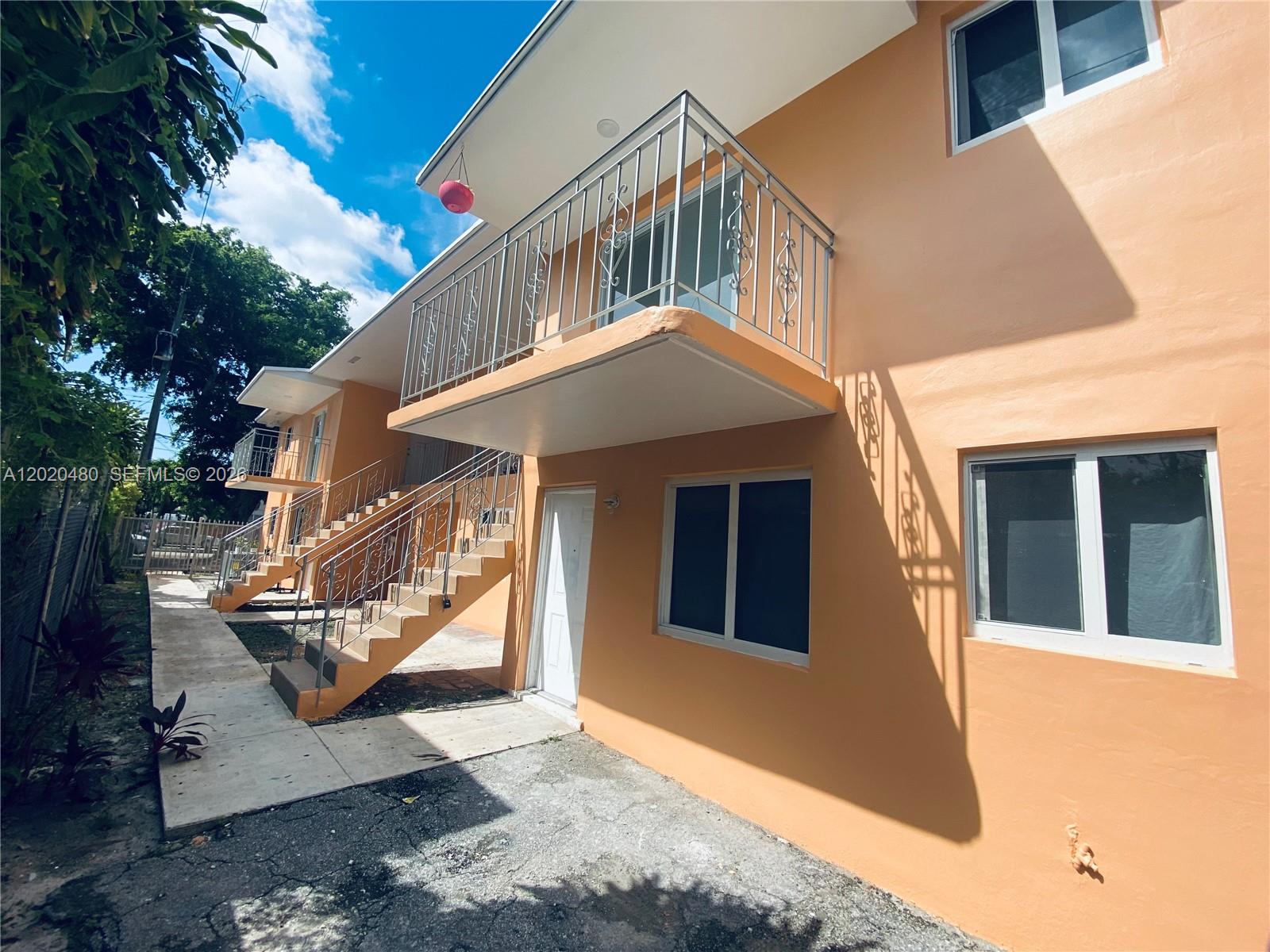 An exterior view of a two-story orange apartment building with metal balcony railings and stairs — 1121 NW 4  ST, Miami FL 33128, MIAMI, FL
