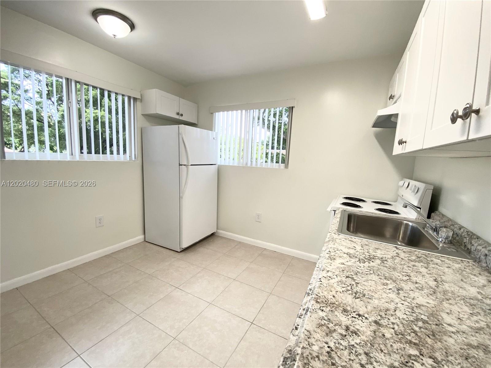 A kitchen features white cabinets, a granite countertop, a stainless steel sink, and white appliances — 1121 NW 4  ST, Miami FL 33128, MIAMI, FL