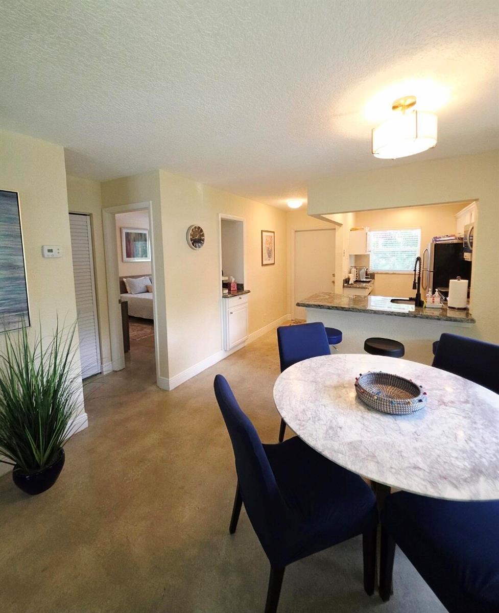 A dining area with a marble table and blue chairs overlooks an open-concept kitchen — 207 Tropic Isle Drive # 215, Delray Beach FL 33483, DELRAY BEACH, FL