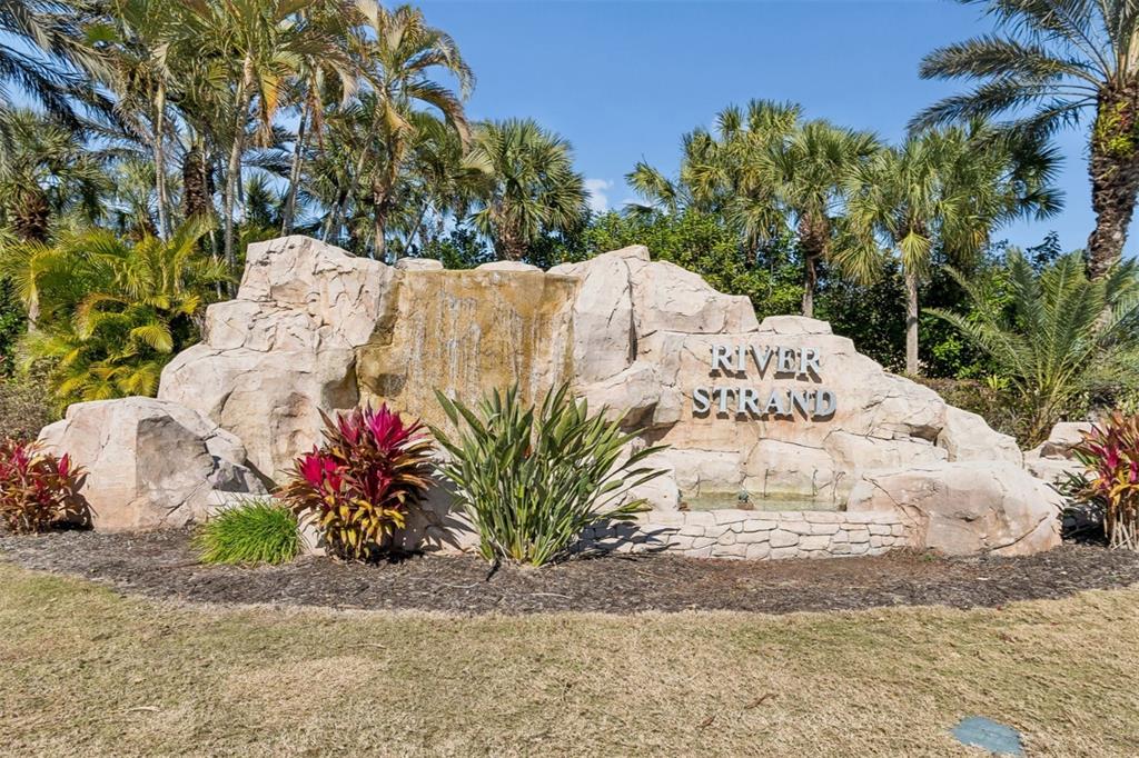 A large rock waterfall feature serves as the entrance sign for the River Strand community — 7607 GRAND ESTUARY TRAIL UNIT 302, BRADENTON, FL