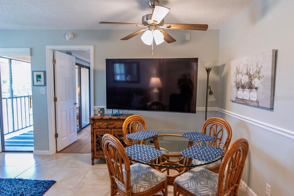 A dining area features a glass-topped table with four rattan chairs beneath a ceiling fan — 19505 QUESADA AVENUE UNIT RR202, PORT CHARLOTTE, FL