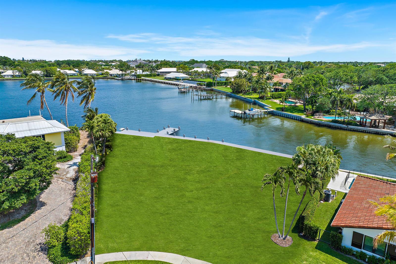 An aerial view shows a vacant grassy waterfront lot with a dock and palm trees — 1454 Point Way, North Palm Beach FL 33408, NORTH PALM BEACH, FL