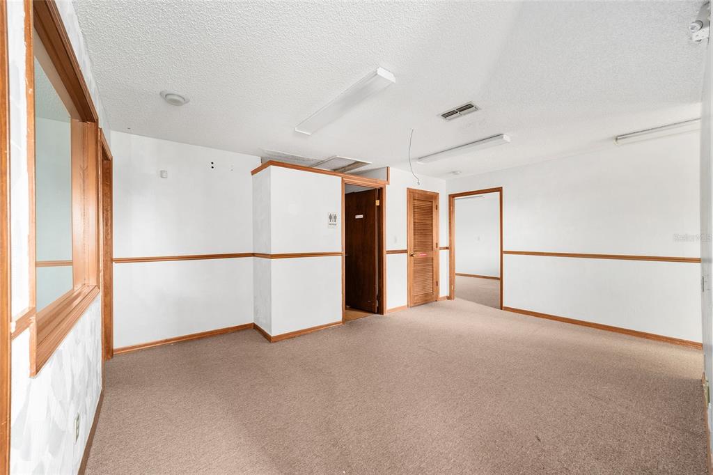An interior view of an office space with beige carpeting, white walls, and wood trim — 2801 SW COLLEGE ROAD UNIT 5, OCALA, FL