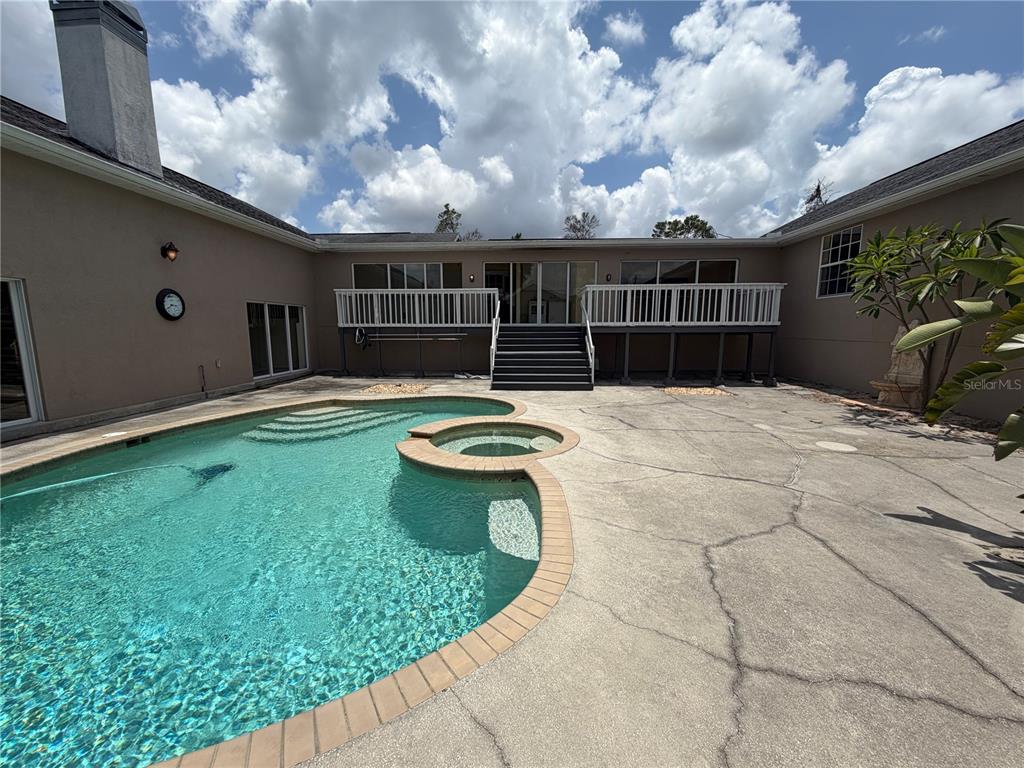 A backyard features a swimming pool with an attached spa and a raised wooden deck — 7941 SYCAMORE DRIVE, NEW PORT RICHEY, FL