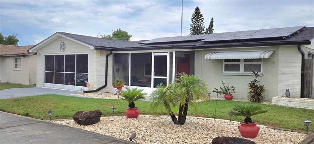 A single-story house features a screened-in garage, a front porch, and solar panels on the roof — 3111 KILBURN ROAD, HOLIDAY, FL
