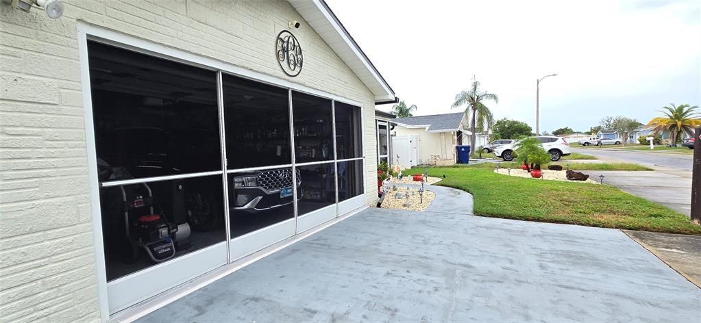 A garage with a screen door enclosure and a concrete driveway in a residential neighborhood — 3111 KILBURN ROAD, HOLIDAY, FL
