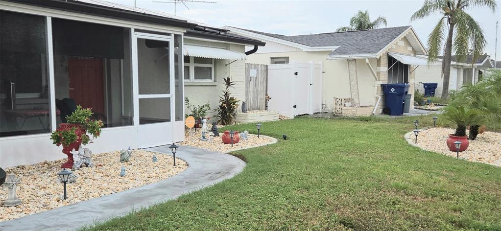 A view of the exterior of a house with a screened porch and landscaped yard — 3111 KILBURN ROAD, HOLIDAY, FL