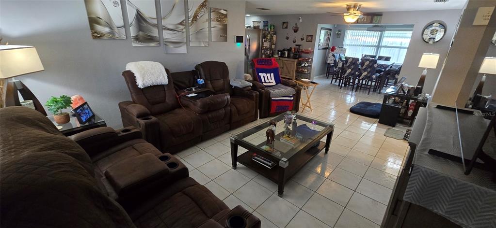 A living room with brown reclining furniture, a glass coffee table, and tiled flooring — 3111 KILBURN ROAD, HOLIDAY, FL