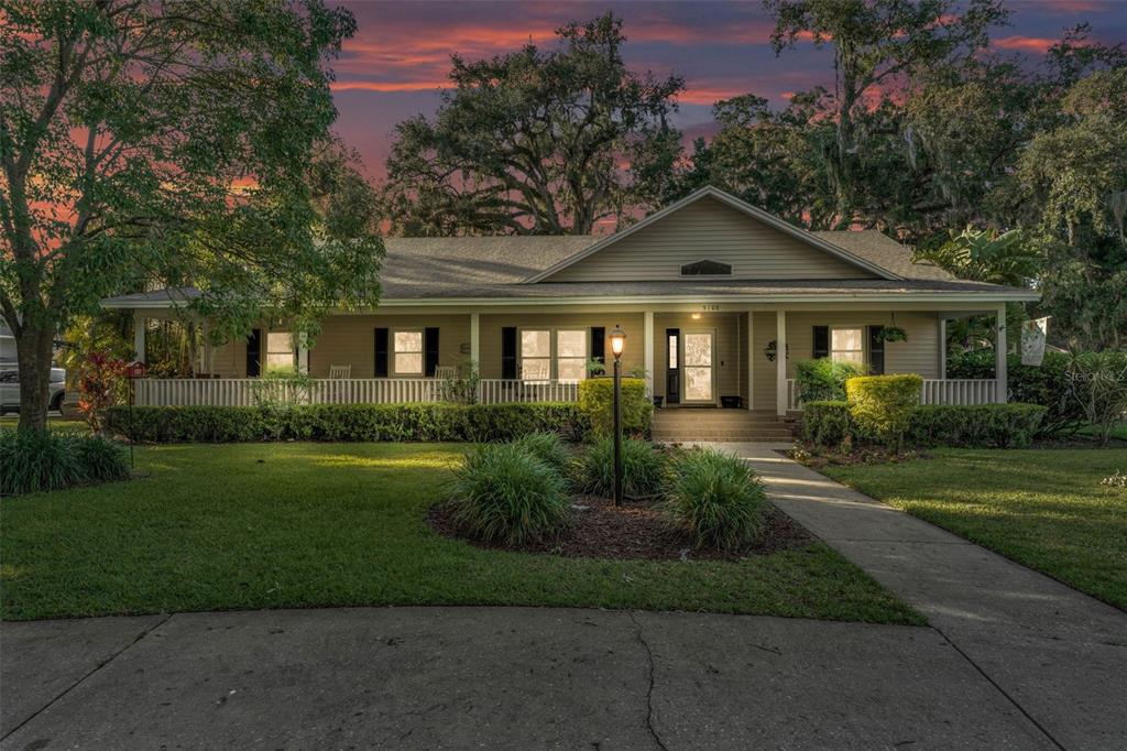 A single-story house with a wide front porch and a concrete walkway at sunset — 5108 WATERWOOD DRIVE, BARTOW, FL