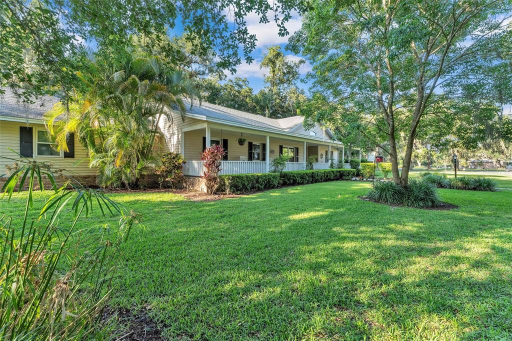 A single-story house with a wrap-around porch sits on a large, grassy, tree-filled lot — 5108 WATERWOOD DRIVE, BARTOW, FL