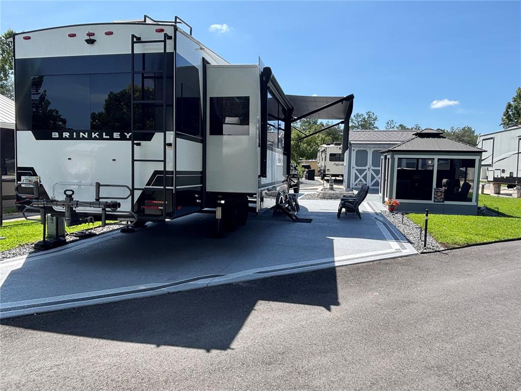 A Brinkley RV is parked on a paved lot next to a small gazebo — 2850 NE 103RD TERRACE, SILVER SPRINGS, FL