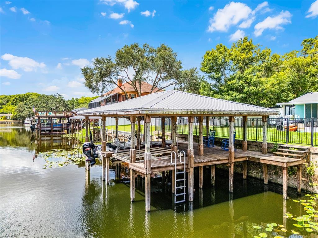 A covered wooden boat dock sits on a lake with a ladder and seating area — 1811 MISSOURI AVENUE, SANFORD, FL