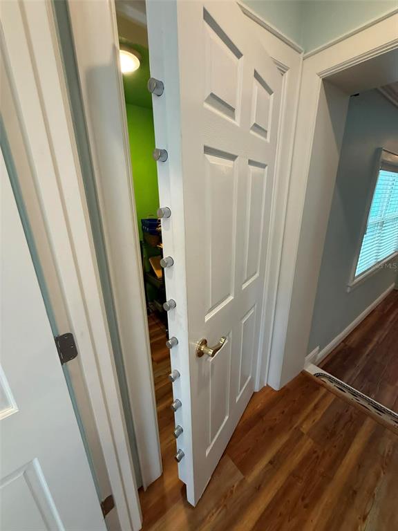 A white door with multiple locking bolts is slightly ajar, revealing a small green room — 1811 MISSOURI AVENUE, SANFORD, FL