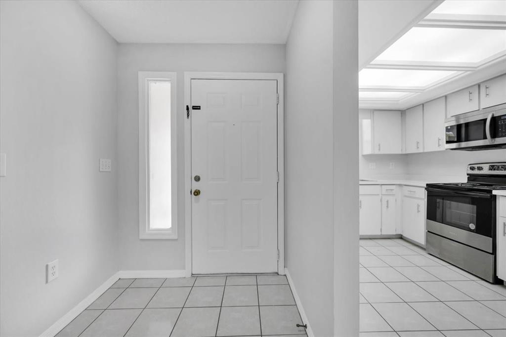 A white front door opens into a tiled entryway adjacent to a white kitchen — 2025 SYLVESTER ROAD UNIT MM4, LAKELAND, FL