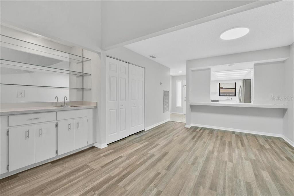 A room with light wood-look flooring, a wet bar with glass shelves, and a pass-through window — 2025 SYLVESTER ROAD UNIT MM4, LAKELAND, FL