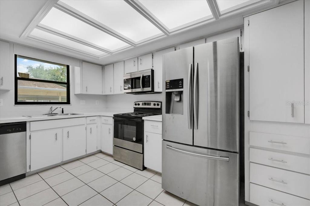A kitchen features white cabinets, stainless steel appliances, and light-colored tile flooring — 2025 SYLVESTER ROAD UNIT MM4, LAKELAND, FL