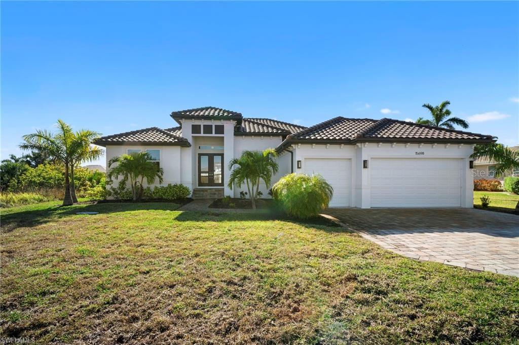 A single-story house with a tiled roof, white stucco exterior, and a two-car garage — 15698 MEACHAM CIRCLE, PORT CHARLOTTE, FL
