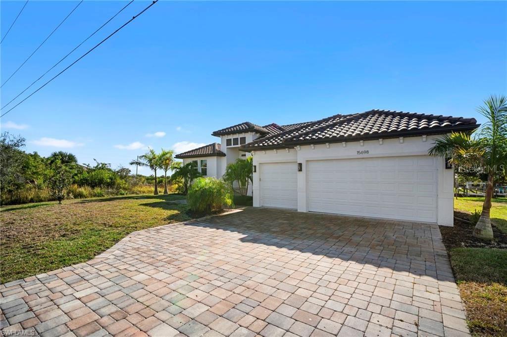 A single-story house with a tiled roof, white exterior, and a paved driveway — 15698 MEACHAM CIRCLE, PORT CHARLOTTE, FL