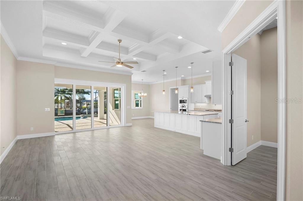 An open-concept living area features a coffered ceiling, tile flooring, and a white kitchen — 15698 MEACHAM CIRCLE, PORT CHARLOTTE, FL