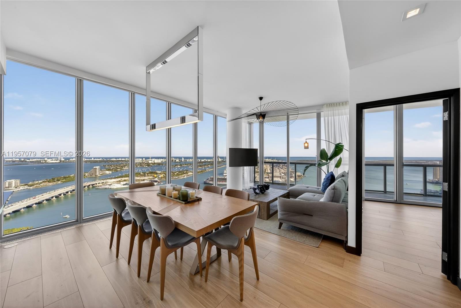 A dining and living area features floor-to-ceiling windows with panoramic water and city views — 888 Biscayne Blvd # 5508, Miami FL 33132, MIAMI, FL