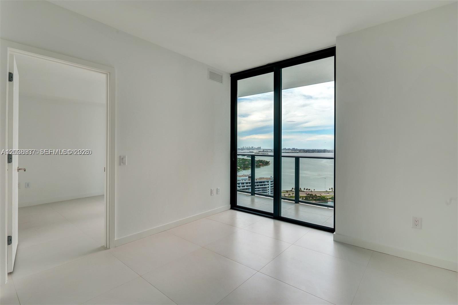 An empty room with white tile floors, a doorway, and a balcony overlooking the water — 501 NE 31st St # 3505, Miami FL 33137, MIAMI, FL