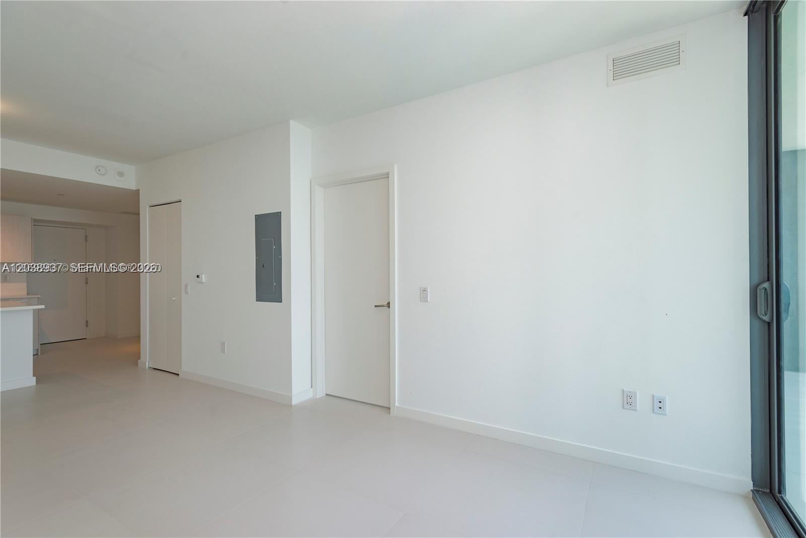 A minimalist room features white walls, tile flooring, a closed door, and an electrical panel — 501 NE 31st St # 3505, Miami FL 33137, MIAMI, FL