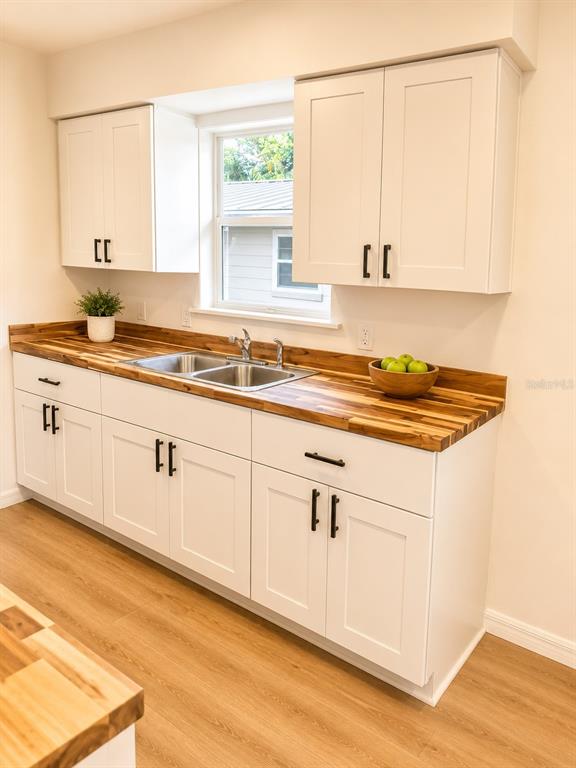 A kitchen features white shaker cabinets, a wood countertop, and a stainless steel sink — 1016 W 8TH STREET, SANFORD, FL