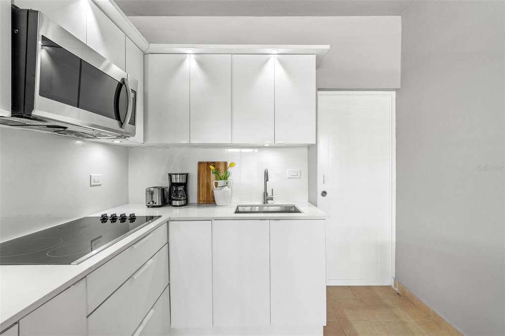 A modern kitchen features white cabinets, stainless steel appliances, and a glass cooktop — 56 MARIA MOCZO UNIT 1, SAN JUAN, PR