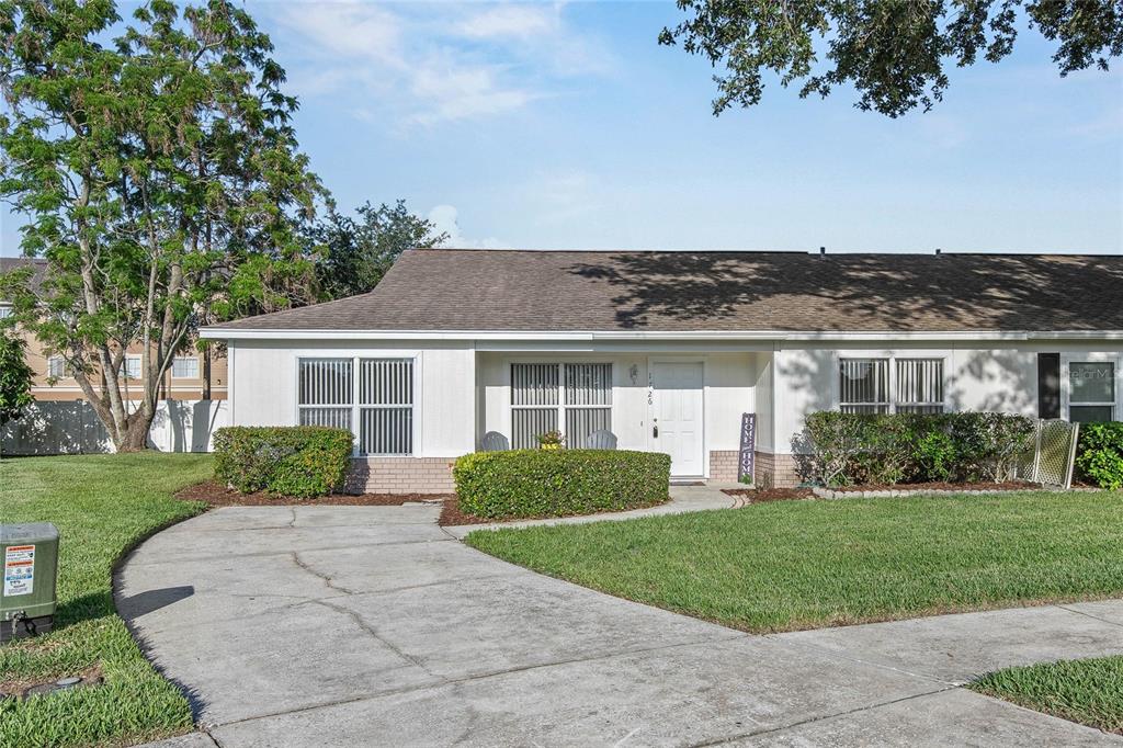 A single-story residential building with a white facade, brick base, and a concrete driveway — 1726 TROPICAL COURT, TAVARES, FL