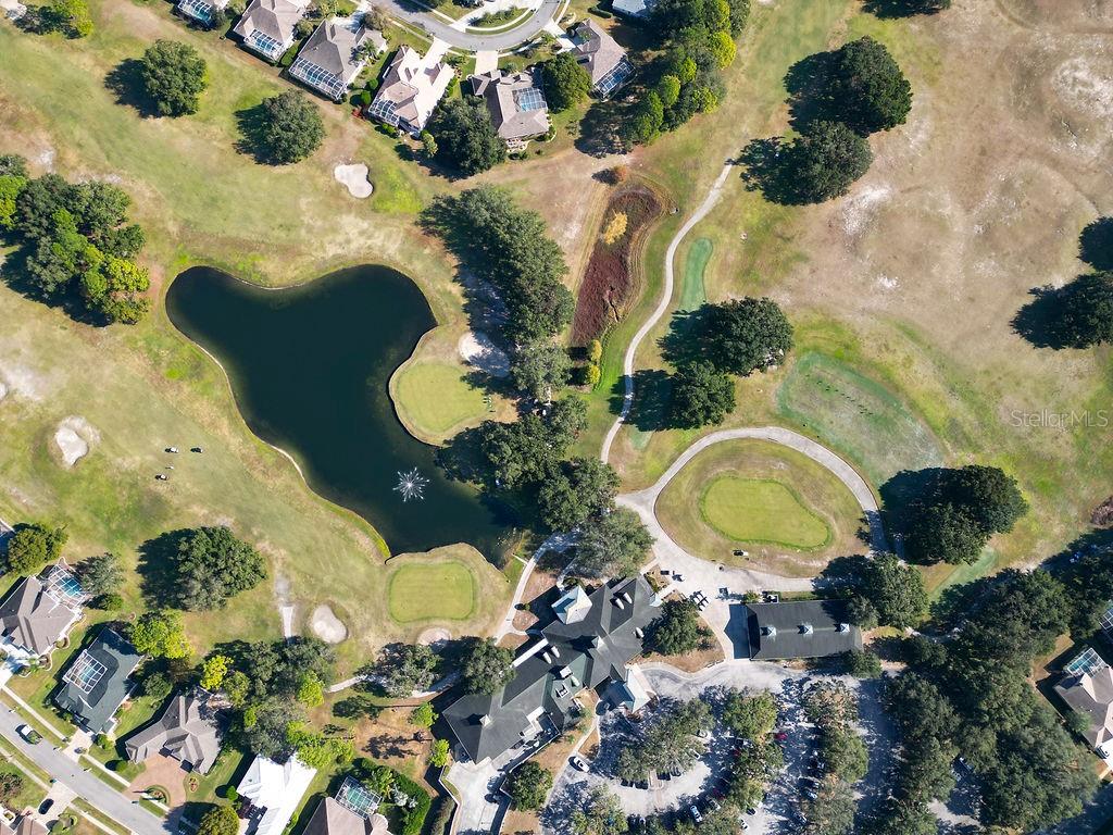 An aerial view shows a large clubhouse, a golf course, a pond, and surrounding houses — 4460 GOLF CLUB LANE, SPRING HILL, FL