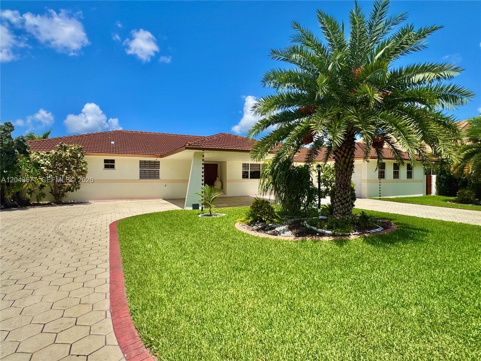 A single-story house with a tiled roof, a paved driveway, and a large palm tree — 18701 Wentworth Dr, Hialeah FL 33015, HIALEAH, FL