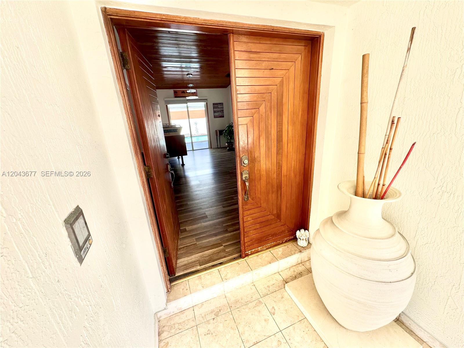 A wooden double door opens into a room with wood-look flooring and a ceiling — 18701 Wentworth Dr, Hialeah FL 33015, HIALEAH, FL