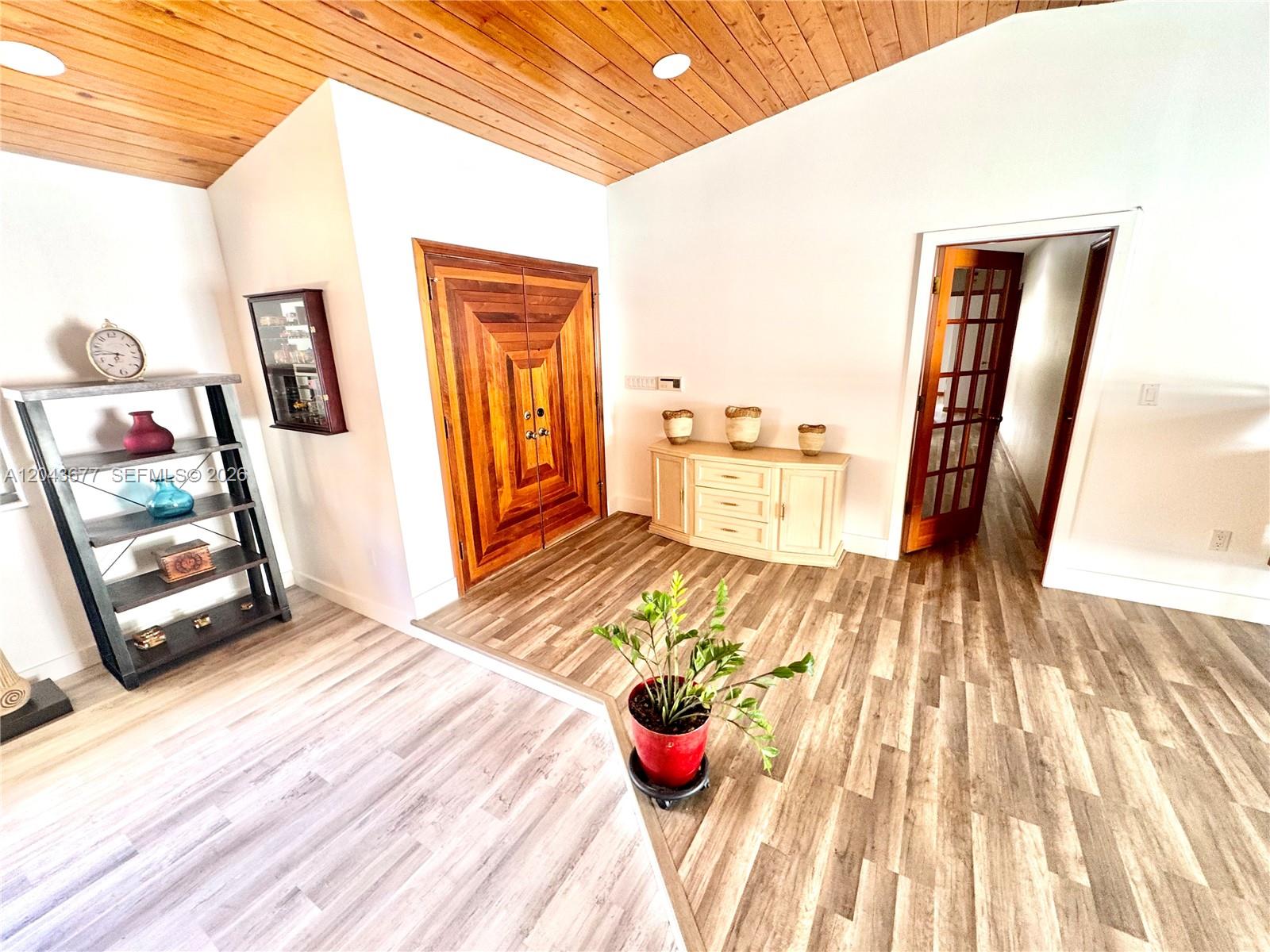 An entryway features a wood-paneled vaulted ceiling, double wood doors, and two-toned flooring — 18701 Wentworth Dr, Hialeah FL 33015, HIALEAH, FL
