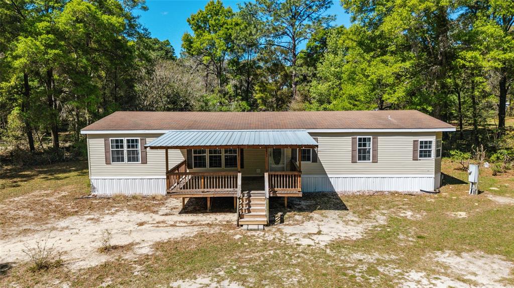 A single-story manufactured home with light siding, a metal-roofed front porch, and surrounding trees — 8415 SW 41ST PLACE ROAD, OCALA, FL