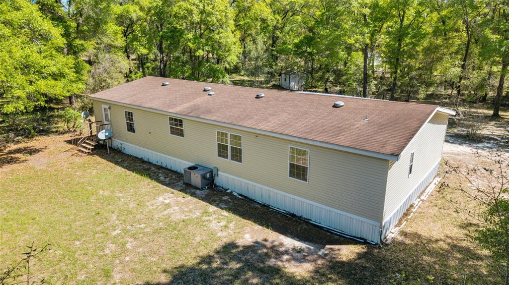 An aerial view of a tan manufactured home with a brown roof in a wooded lot — 8415 SW 41ST PLACE ROAD, OCALA, FL