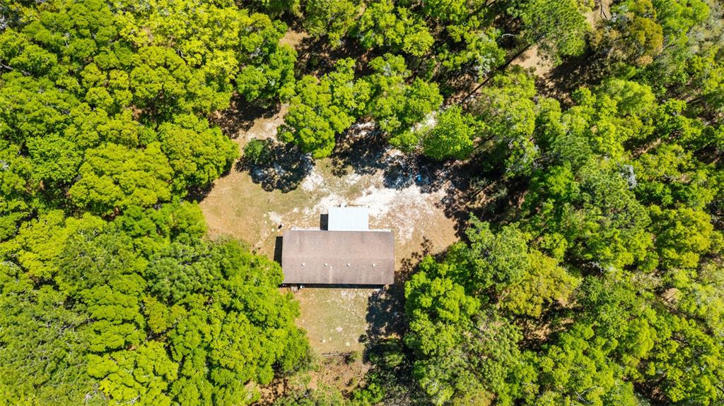 An aerial view shows a rectangular house with a brown roof surrounded by dense forest — 8415 SW 41ST PLACE ROAD, OCALA, FL