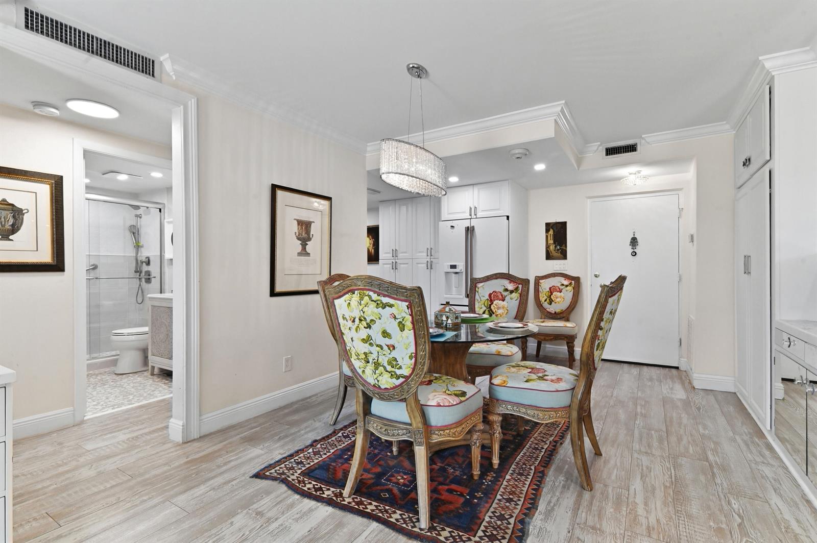 A dining area features a glass table, floral chairs, a patterned rug, and white cabinetry — 2840 S Ocean Boulevard # 109, Palm Beach FL 33480, PALM BEACH, FL
