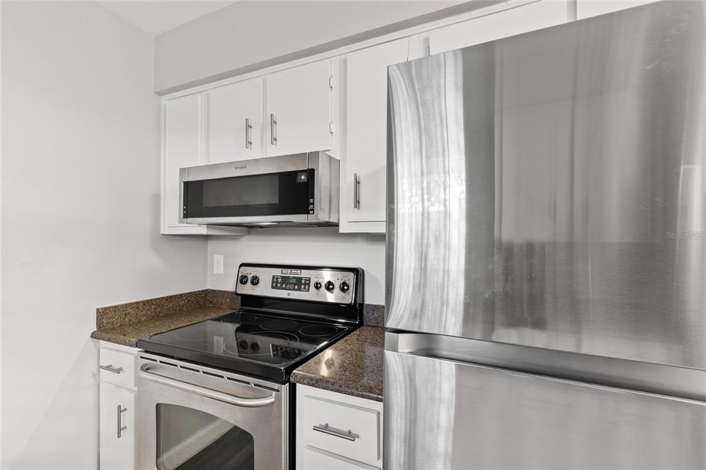 A kitchen features white cabinets, stainless steel appliances, and dark brown granite countertops — 308 DORCHESTER SQUARE, LAKE MARY, FL
